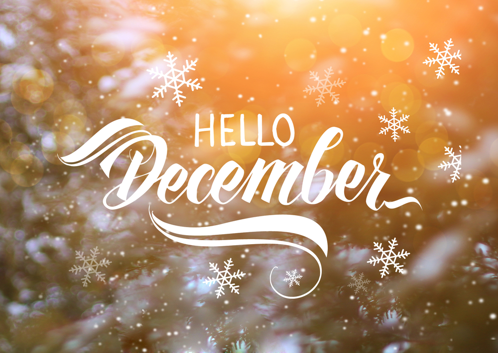 Hello December text with decorative swirls and snowflakes over a warm, blurred background with golden light and bokeh effects, creating a festive, wintery atmosphere.