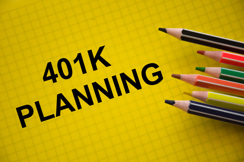 401K Planning text on yellow graph paper, with several colored pencils arranged in the top right corner.