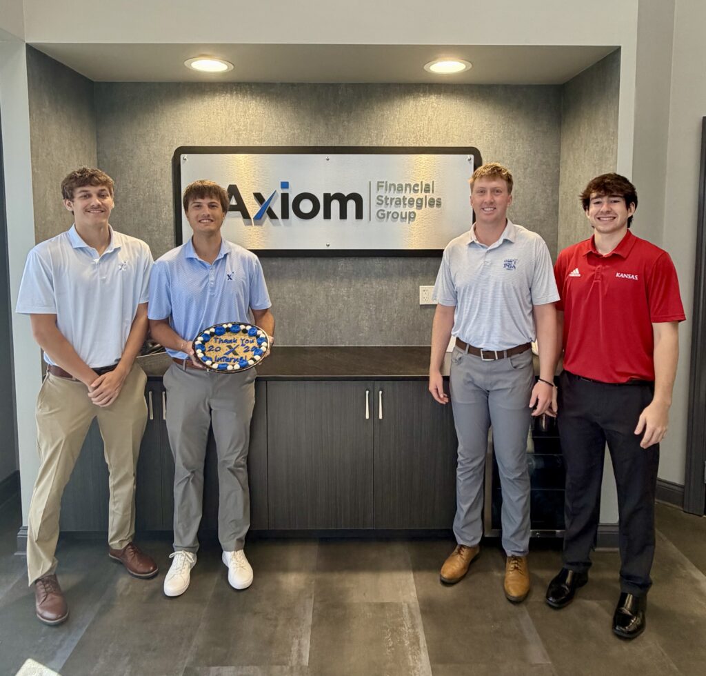 Four men stand smiling in business casual attire in front of an Axiom Financial Strategies Group sign, highlighting opportunities like finance jobs New Albany. One man holds a decorated plate. The setting appears to be a professional office lobby.