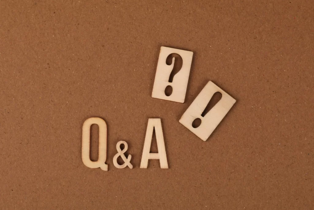 Wooden cutouts of the letters Q & A are arranged on a brown surface, with a wooden question mark and exclamation mark placed above them.