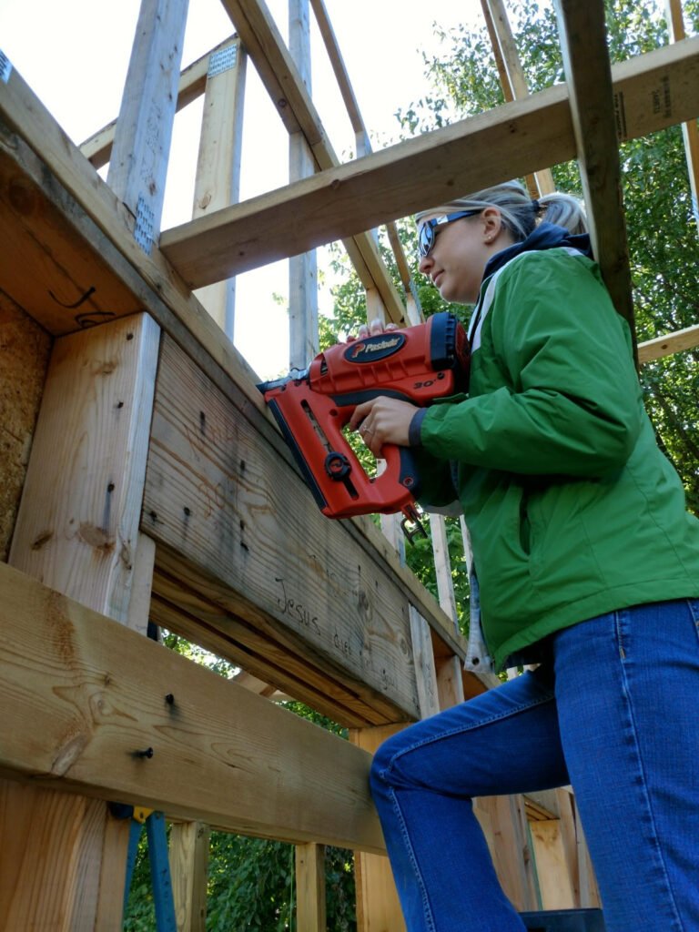 Michelle uses a nailgun to secure Habitat house